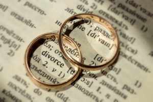 Two separate wedding rings next to the word "divorce". The concept of divorce, parting, infidelity . Selective focus.